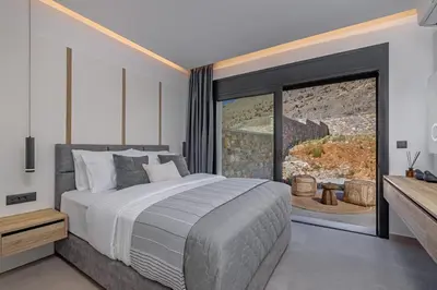 a bedroom with a bed and a large window at Amani Villas Lindos in Líndos