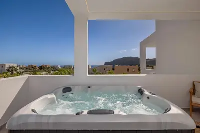a bath tub in a room with a large window at Amani Villas Lindos in Líndos
