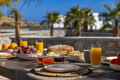 a table with food and orange juice and fruit on it at Amani Villas Lindos in Líndos