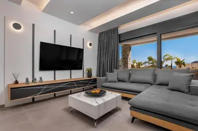 a living room with a couch and a tv at Amani Villas Lindos in Líndos