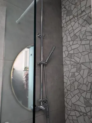 a bathroom with a round mirror and a shower at Nirea Tree View Studio in Faliraki