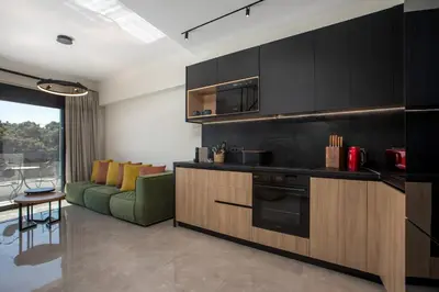 a kitchen with black cabinets and a green couch at Rodos Nest with terrace and seaview in Asgourou