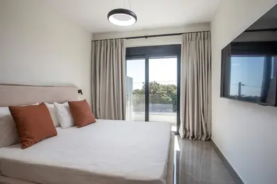 a bedroom with a white bed and a large window at Rodos Nest with terrace and seaview in Asgourou