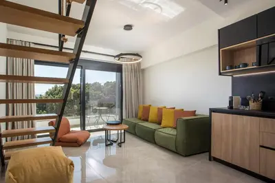 a living room with a green couch and a large window at Rodos Nest with terrace and seaview in Asgourou