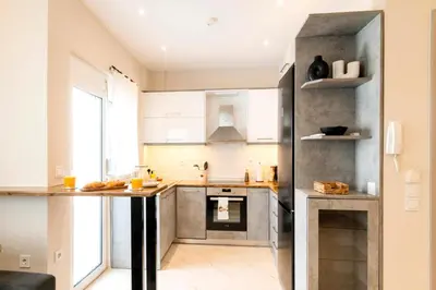 a kitchen with white cabinets and a black refrigerator at Acropolis Gem in Rhodes Town