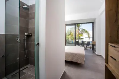 a bedroom with a bed and a glass shower at Moscha Hotel in Faliraki