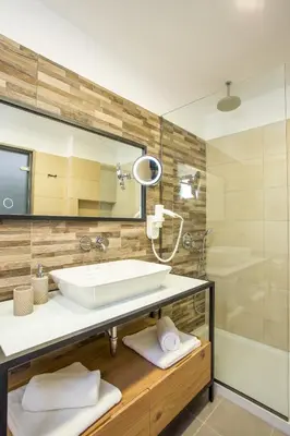 a bathroom with a sink and a mirror and a tub at Moscha Hotel in Faliraki