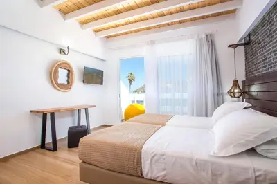 a bedroom with a bed and a table and a window at Moscha Hotel in Faliraki
