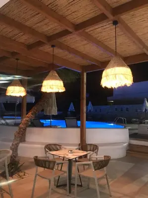 a patio with a table and chairs and lights at Moscha Hotel in Faliraki
