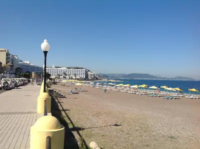 a beach with chairs and umbrellas and a street light at City center beach house in Rhodes Town