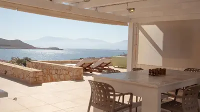 a patio with a table and chairs and a view of the water at Villa Aristoteles in Halki