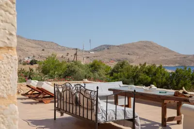 a patio with a table and chairs and a view of the water at Villa Aristoteles in Halki