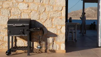 a charcoal grill sitting next to a stone wall at Villa Blu Majestic beach villa in Halki