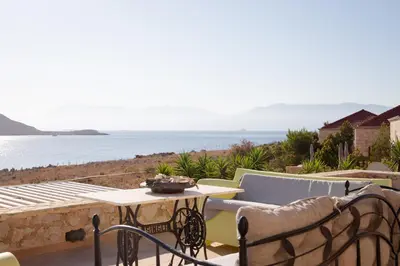 a patio with a table and chairs and the ocean at Villa Blu Majestic beach villa in Halki