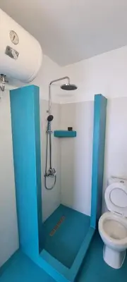 a bathroom with a toilet and a blue shower stall at St Paul's Studios Chrysanthi in Líndos