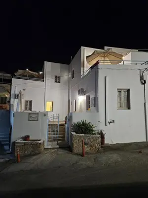 a white building with a gate and an umbrella at St Paul's Studios Chrysanthi in Líndos