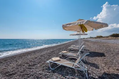 a group of chairs and an umbrella on a beach at Great Sand Villa in Gennadi