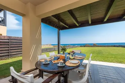 a dining table on a patio with a view of the ocean at Great Sand Villa in Gennadi