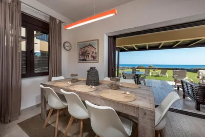a dining room with a table and chairs and a large window at Great Sand Villa in Gennadi