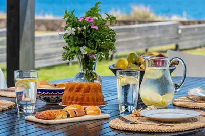 a table with bread and juice and a vase of flowers at Great Sand Villa in Gennadi