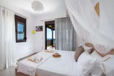 a white bedroom with a bed with towels on it at Great Sand Villa in Gennadi