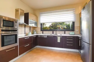 a large kitchen with brown cabinets and a window at Villa Kallisti Ialyssos by Villa Plus in Triánta