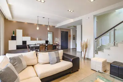 a living room with a couch and a dining room at Villa Kallisti Ialyssos by Villa Plus in Triánta