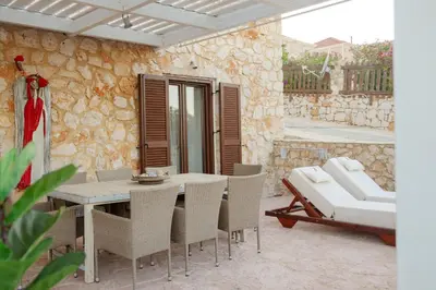 a patio with a table and chairs and a couch at Belvedere private luxury beach villa in Halki