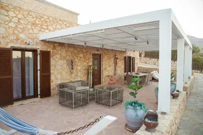a patio with a white pergola and a table and chairs at Belvedere private luxury beach villa in Halki
