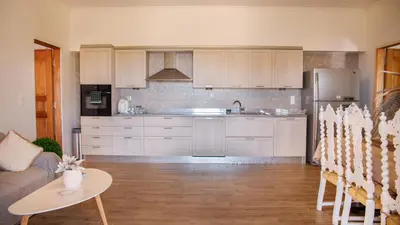 a kitchen with white cabinets and a table and a couch at Belvedere private luxury beach villa in Halki