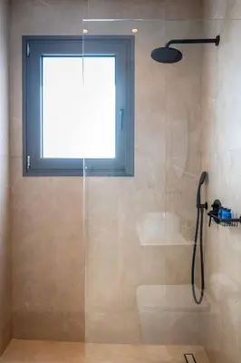 a bathroom with a shower with a glass door at Alati Suites - Stegna Beach in Vrachonisída touArchangélou