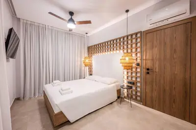 a bedroom with a white bed and a wooden wall at Alati Suites - Stegna Beach in Vrachonisída touArchangélou