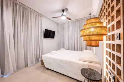 a bedroom with a bed and a chandelier at Alati Suites - Stegna Beach in Vrachonisída touArchangélou