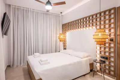 a bedroom with a white bed and two lamps at Alati Suites - Stegna Beach in Vrachonisída touArchangélou
