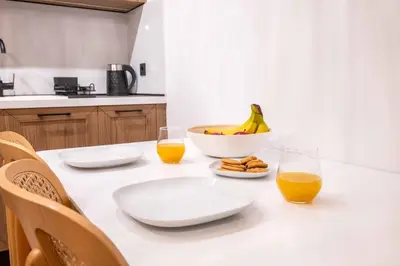 a table with a bowl of bananas and two glasses of orange juice at Alati Suites - Stegna Beach in Vrachonisída touArchangélou