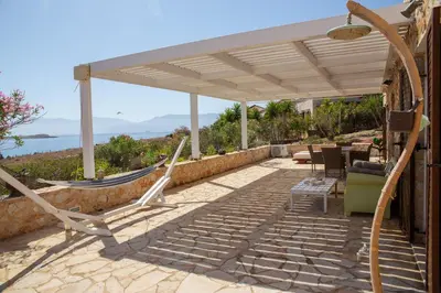 a patio with a hammock under a pergola at Villa Romanza beach villa in Halki