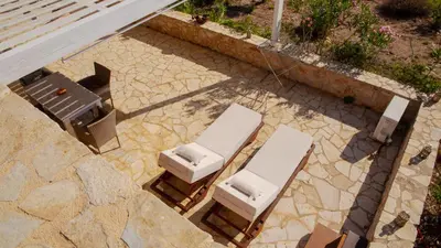 two lounge chairs and a table on a patio at Villa Romanza beach villa in Halki