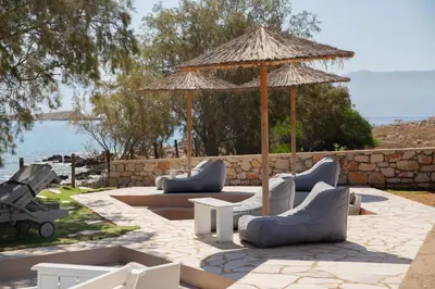 a patio with couches and an umbrella and a table at Villa Romanza beach villa in Halki