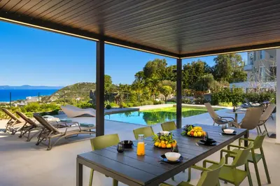 a patio with a table and chairs and a pool at Vista by Del Sol Villa in Rhodes Town