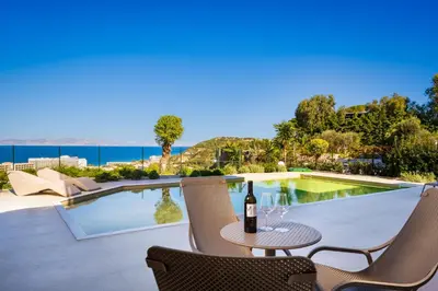 a patio with a table with a bottle of wine at Vista by Del Sol Villa in Rhodes Town