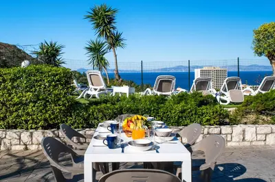a white table and chairs with a view of the ocean at Vista by Del Sol Villa in Rhodes Town