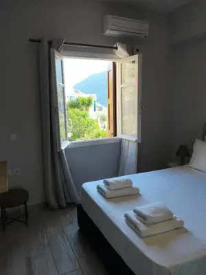 a bedroom with a large window with towels on a bed at Anasa house in Symi