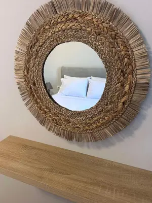a round mirror on a wall with a bed at Anasa house in Symi