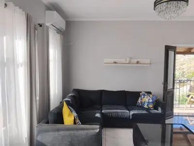 a living room with a black couch and a glass table at Anasa house in Symi