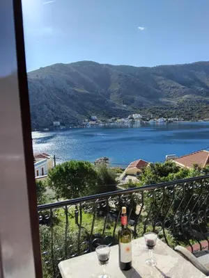 a table with wine glasses and a view of a lake at Anasa house in Symi
