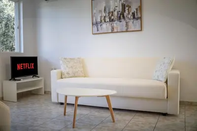 a living room with a white couch and a table at Fotis House 3 in Afantou