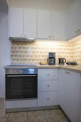 a kitchen with white cabinets and a black oven at Fotis House 3 in Afantou