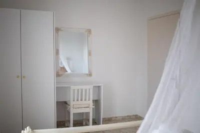 a white room with a chair and a mirror at Fotis House 3 in Afantou