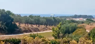 an airplane is flying over a field with trees at ''Aetheria'' Rooftop Resort with sea view in Kremasti