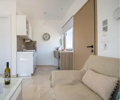 a living room with a couch and a kitchen at ''Aetheria'' Rooftop Resort with sea view in Kremasti